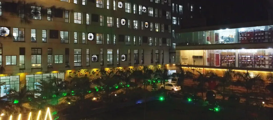 The factory building at dusk, its garden lit in green