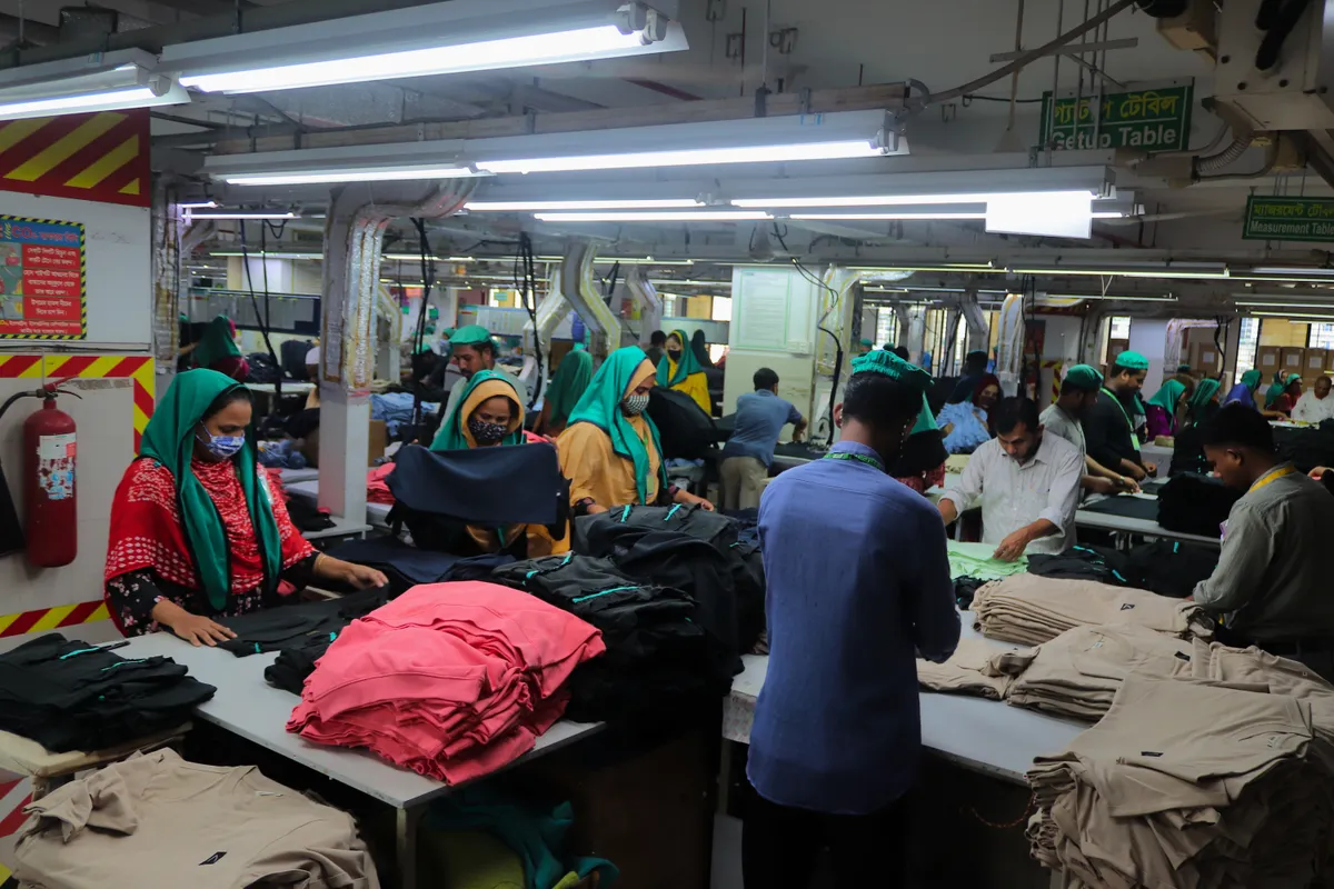 Long finishing tables with workers inspecting garments on both sides