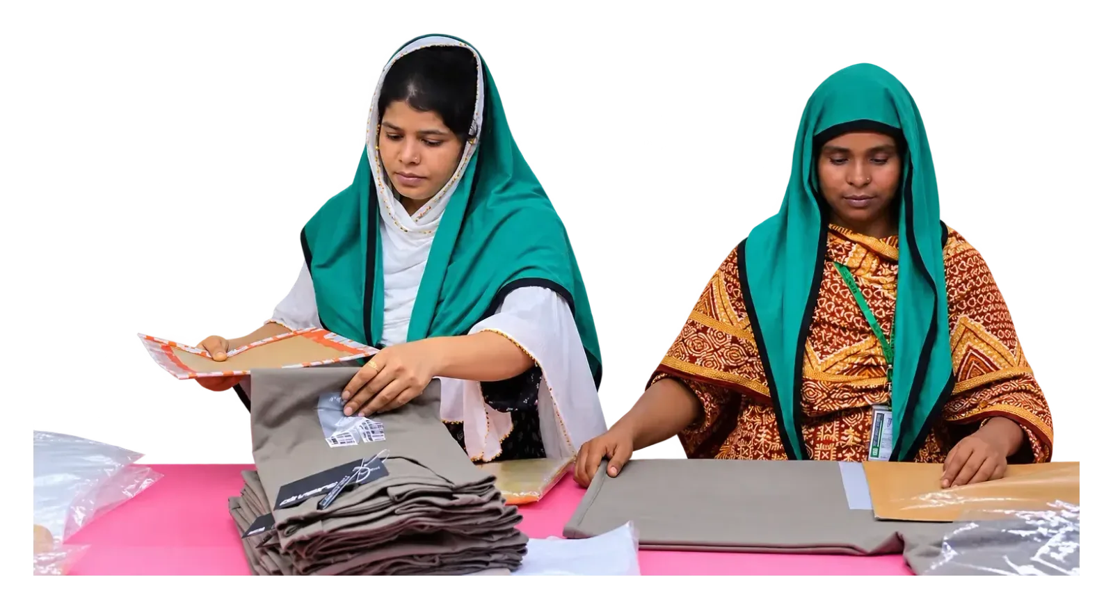 Two workers bagging and tagging folded garments at a packing table